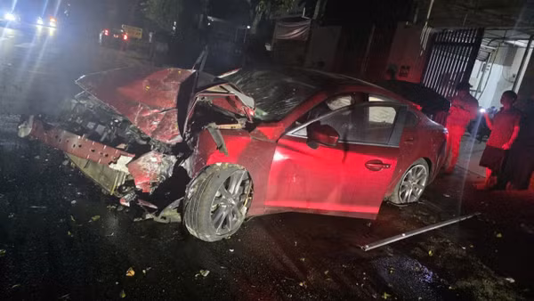 Chiếc xe ô-tô Mazda 6 sau khi tông sập cổng nhà dân bị hư hỏng nặng phần đầu. (Ảnh: CTV)