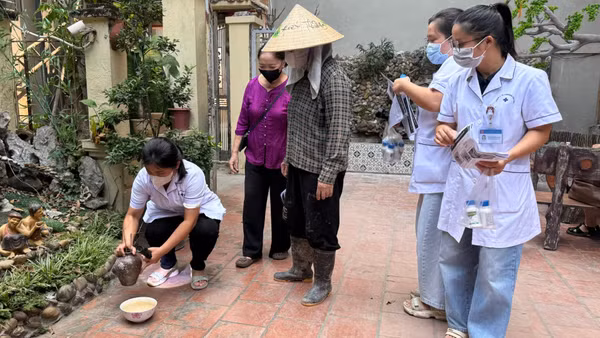 Cán bộ y tế hướng dẫn người dân lược bỏ các vật dụng cụ chứa nước không cần thiết để phòng bệnh sốt xuất huyết. (Ảnh: THẮNG ĐẠT)