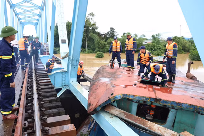 Lực lượng chức năng tiến hành cắt phần mái sà lan bị mắc kẹt với cầu đường sắt. (Ảnh: Công an tỉnh Quảng Trị)