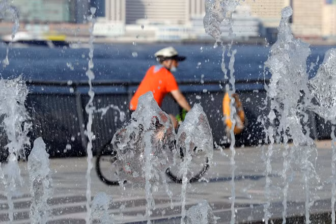 Người dân đạp xe ngang qua đài phun nước trong một ngày nóng nực ở Hong Kong (Trung Quốc), ảnh chụp ngày 24/7/2022. (Ảnh: XINHUA)