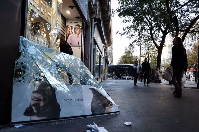 Người dân đi ngang qua một cửa hàng bị hư hại trong một cuộc biểu tình tại Paris, Pháp, ngày 18/10/2026. (Ảnh: XINHUA)
