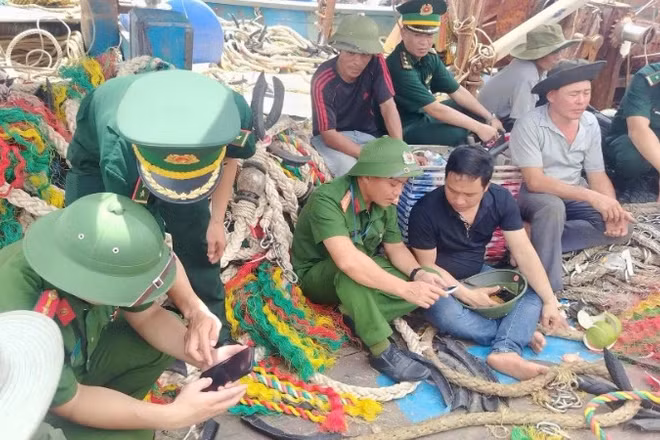 Chiến sĩ Đồn Biên phòng Quỳnh Phương phối hợp với lực lượng công an triển khai “Bình dân học vụ số” cho các thuyền viên trên tàu cá.