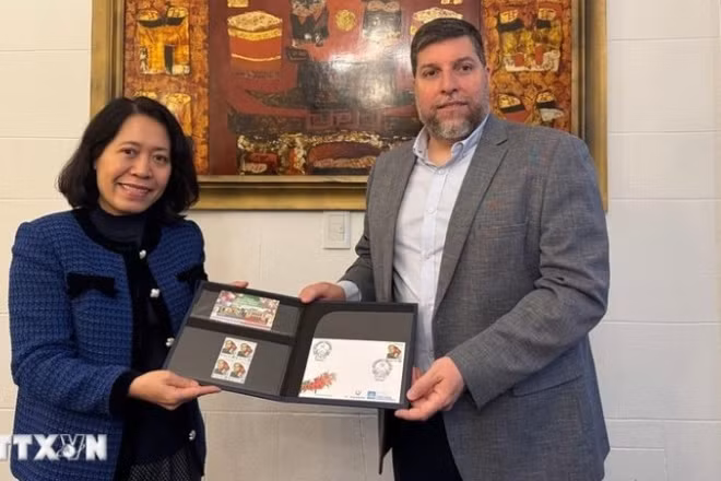 Nghị sĩ Victor Aldaya trao Đại sứ Ngô Minh Nguyệt bộ tem do Bưu chính Uruguay phát hành tháng 12/2013, nhân kỷ niệm 20 năm quan hệ ngoại giao Việt Nam-Uruguay, với chân dung của Đại tướng Võ Nguyên Giáp. (Ảnh TTXVN)