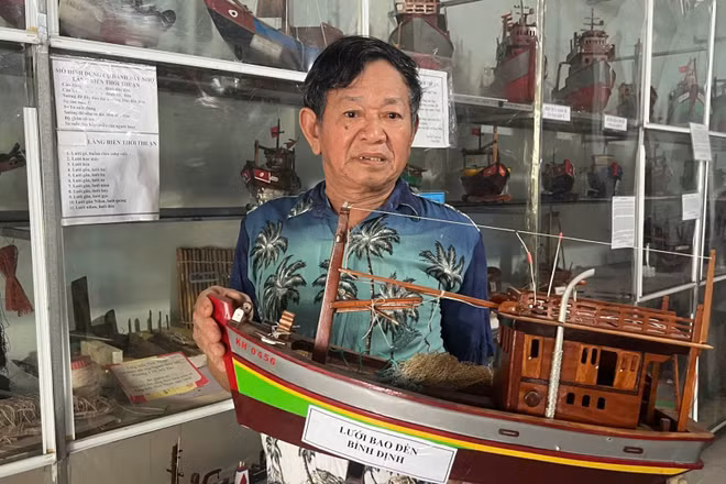 Nghệ nhân Nguyễn Văn Léo bên những chiếc tàu đánh cá gắn liền với cuộc đời mình. (Ảnh: HOÀNG TRUNG)