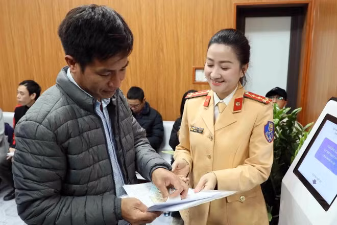 Cán bộ Đội sát hạch, cấp giấy phép lái xe cơ giới đường bộ (Phòng Cảnh sát giao thông, Công an thành phố Hà Nội) hướng dẫn người dân thực hiện thủ tục hành chính. (Ảnh: Thanh Hà)