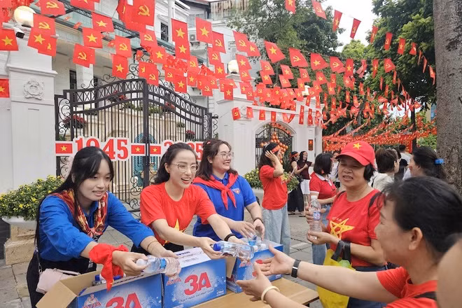 Các bạn tình nguyện viên phát nước cho người dân đi xem sơ duyệt diễu binh, diễu hành tại Hà Nội. (Ảnh: THẾ ĐẠI)