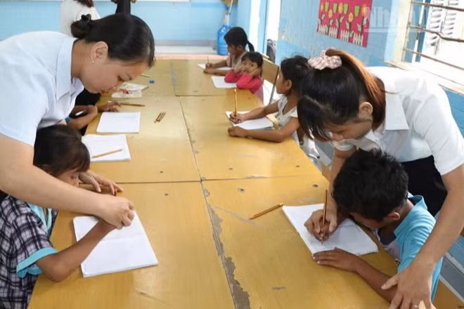 Giáo viên tại điểm trường Suối Hai, Trường tiểu học Cam Phước Đông 1, phường Ba Ngòi, tỉnh Khánh Hòa giúp các em học sinh dân tộc Raglai rèn chữ viết trên lớp học hè. (Ảnh: NGUYỄN TRUNG)