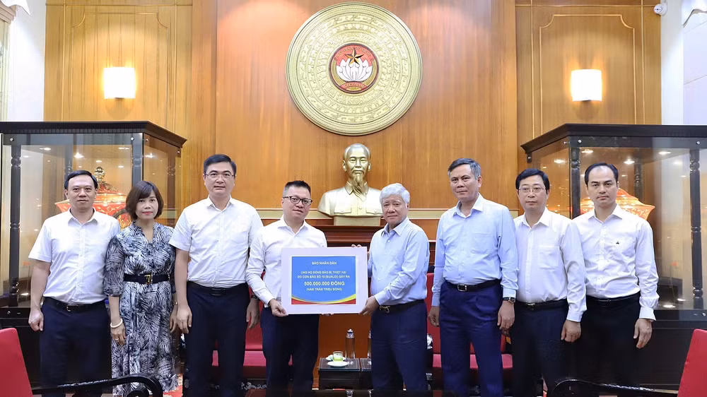 Đồng chí Đỗ Văn Chiến (thứ 4 từ phải sang) tiếp nhận số tiền ủng hộ từ tập thể lãnh đạo, cán bộ, người lao động Báo Nhân Dân.