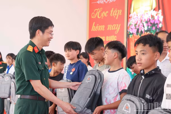 Thiếu tá Trần Văn Hiếu, Giám đốc Chi nhánh Trường Sơn 97 (Binh đoàn 12) trao tặng cặp sách cho học sinh Trường phổ thông nội trú tiểu học và trung học cơ sở Y Tý. (Ảnh: CÔNG HẢI)