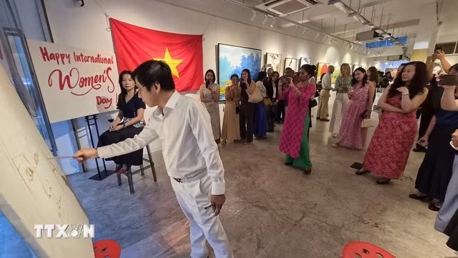 Họa sĩ Phương Quốc Trí thực hiện bức chân dung cho “người mẫu” là một khách mời trong sự kiện. (Ảnh: TTXVN)