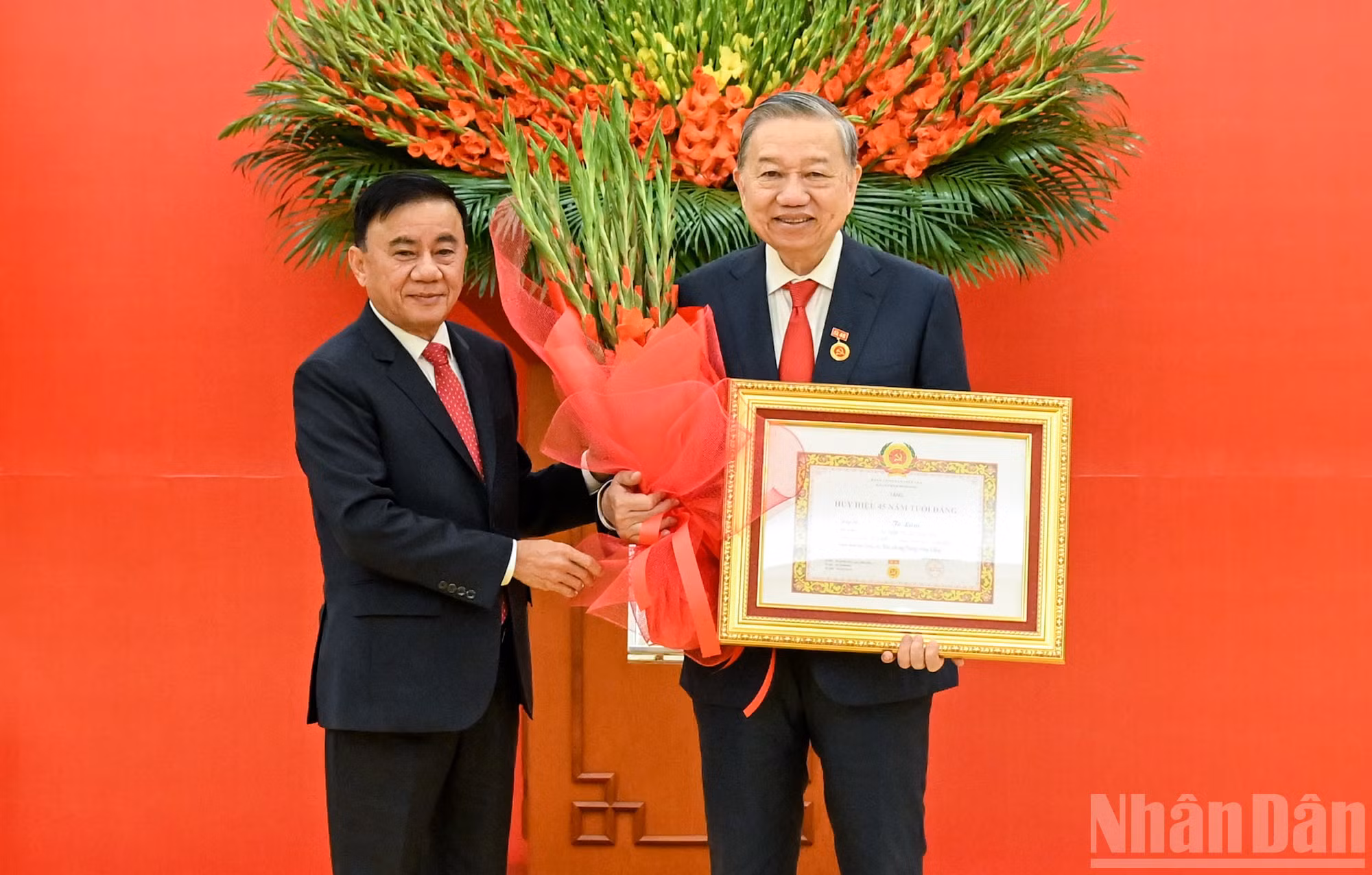 Thường trực Ban Bí thư Trần Cẩm Tú trao huy hiệu 45 năm tuổi đảng, tặng hoa chúc mừng đồng chí Tô Lâm, Tổng Bí thư Ban Chấp hành Trung ương Đảng Cộng sản Việt Nam. (Ảnh: DUY LINH)
