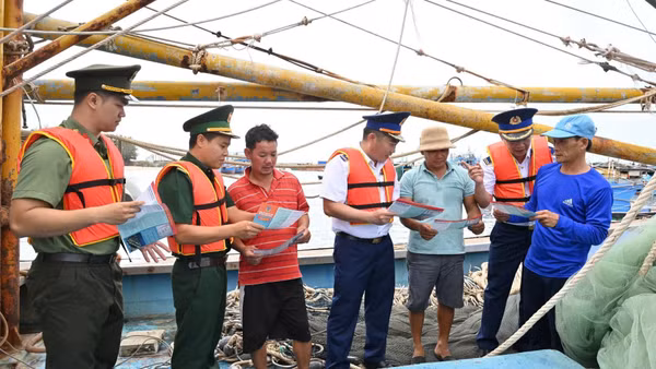Cảnh sát biển và các lực lượng chức năng phát tờ rơi tuyên truyền phòng, chống IUU cho ngư dân. (Ảnh: Cảnh sát biển cung cấp)