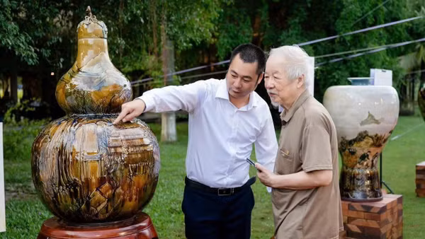 Ông Vũ Đình Mạnh (bên trái) giới thiệu tác phẩm cho khách tham quan.