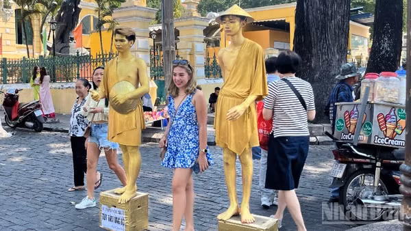 Du khách nước ngoài chụp ảnh lưu niệm tại khu vực trước Bưu điện trung tâm Thành phố. (Ảnh: LINH BẢO)