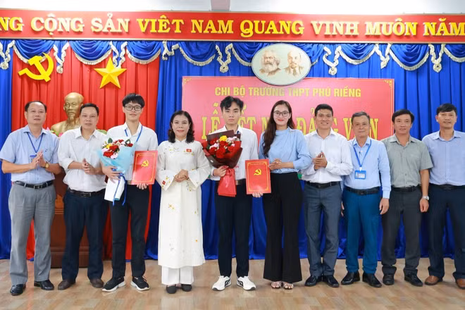 Bí thư Đảng ủy xã Phú Riềng cùng các đồng chí trong Chi bộ Trường trung học phổ thông Phú Riềng tặng hoa chúc mừng 2 đảng viên mới.
