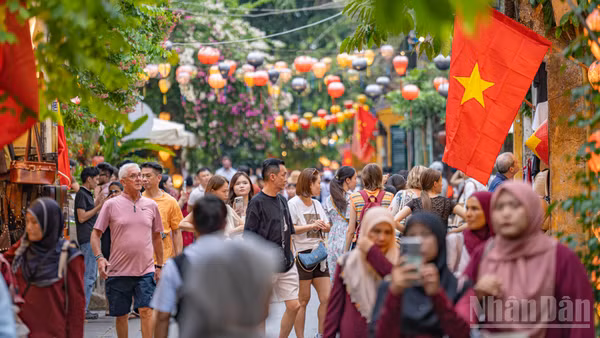 Lá Quốc kỳ tung bay trên những tuyến phố đông nghẹt người khiến không gian phố cổ Hội An trong những ngày này thêm phần trang trọng.