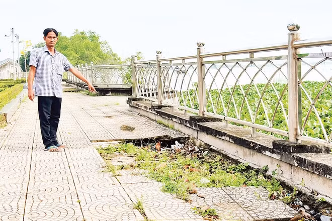 Người dân chỉ nơi sụt lún kè sông Cổ Chiên đoạn phường Tân Ngãi, tỉnh Vĩnh Long.