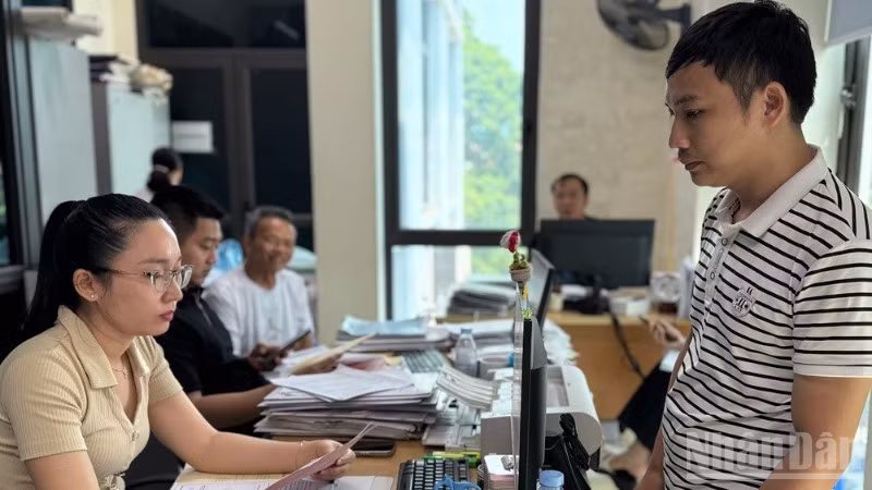Cán bộ Văn phòng Đăng ký đất đai phường Yên Bái thẩm định kết quả và trả giấy chứng nhận quyền sử dụng đất cho công dân trong phường. (Ảnh: THANH SƠN)