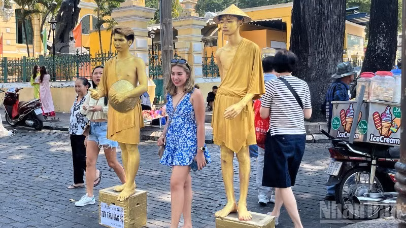 Du khách nước ngoài chụp ảnh lưu niệm tại khu vực trước Bưu điện trung tâm Thành phố. (Ảnh: LINH BẢO)