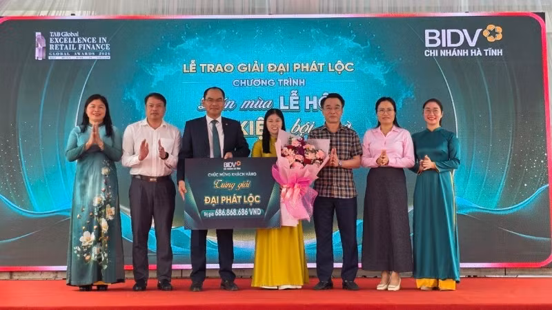 Đại diện lãnh đạo Ngân hàng Nhà nước Việt Nam khu vực 8, BIDV Hà Tĩnh, chính quyền địa phương tặng hoa chúc mừng khách hàng may mắn.