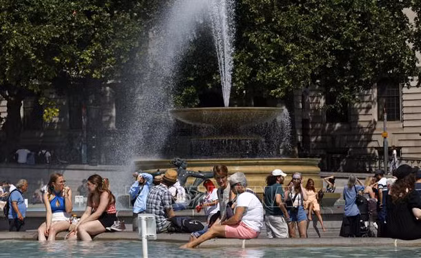 Người dân tránh nóng bên đài phun nước tại Quảng trường Trafalgar ở thủ đô London, Anh, ngày 17/6/2022. (Ảnh: AFP/TTXVN)