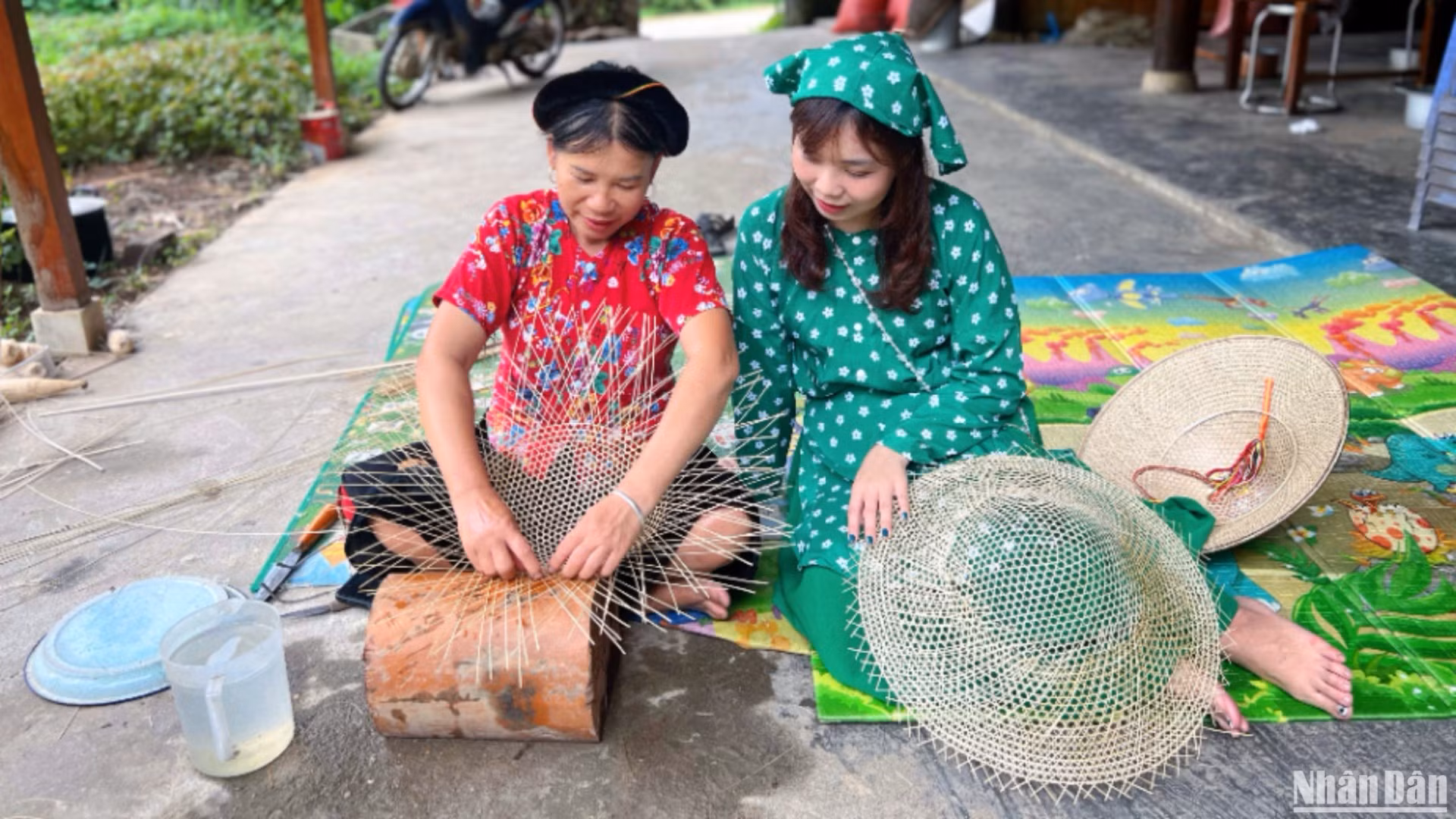 Bà Hoàng Thị Huệ (bên trái) trò chuyện và hướng dẫn khách làm nón.