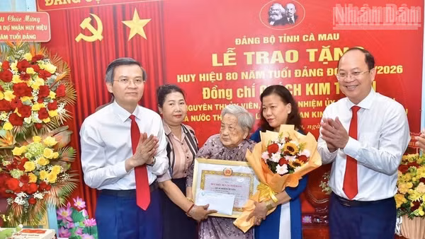 Đồng chí Đoàn Minh Huấn, Ủy viên Bộ Chính trị, Giám đốc Học viện Chính trị quốc gia Hồ Chí Minh (bên trái) và đồng chí Nguyễn Hồ Hải, Bí thư Tỉnh ủy Cà Mau (bên phải) trao Huy hiệu 80 năm tuổi Đảng tặng đồng chí Quách Kim Tuyến, ở phường Bạc Liêu, tỉnh Cà Mau. (Ảnh: PV)