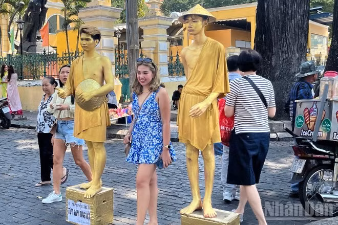 Du khách nước ngoài chụp ảnh lưu niệm tại khu vực trước Bưu điện trung tâm Thành phố. (Ảnh: LINH BẢO)