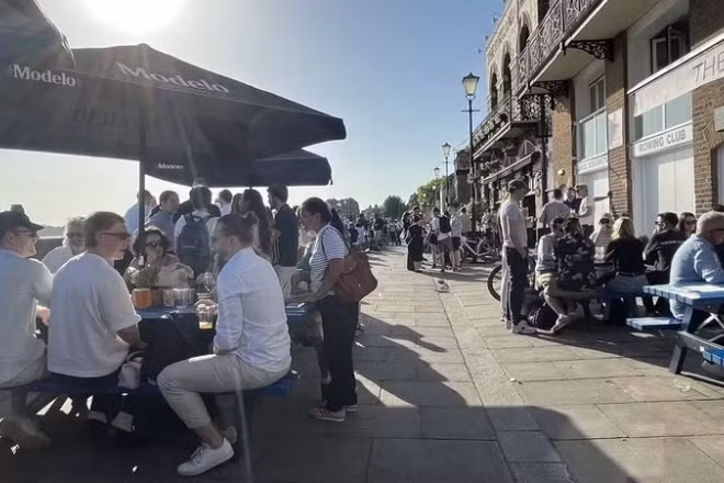 Người dân thưởng thức đồ uống tại các pub ven sông Thames trong ngày nắng nóng. (Ảnh: Hương Giang/TTXVN)