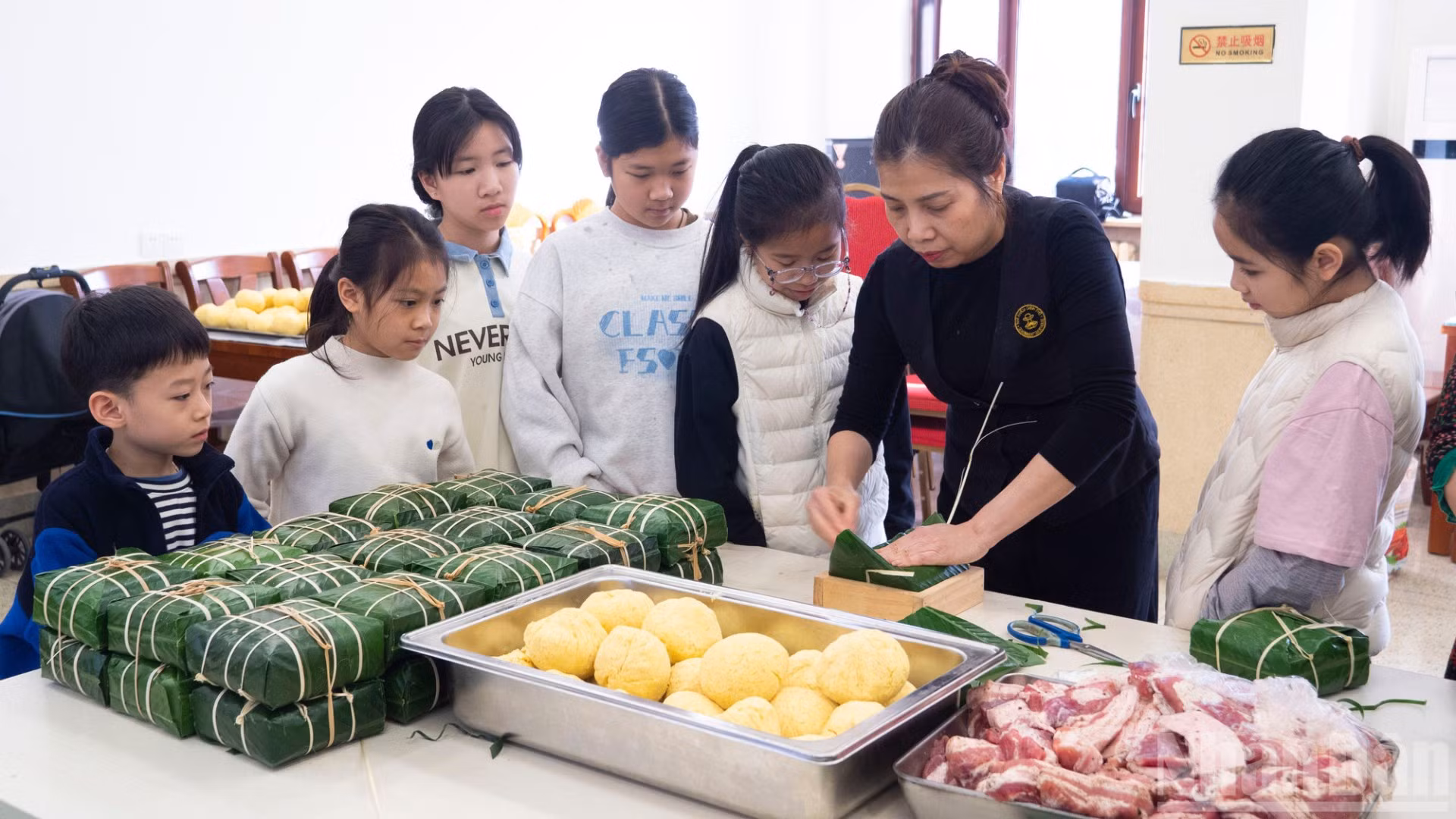 Các cháu thanh thiếu niên, nhi đồng chăm chú theo dõi các khâu gói bánh chưng.