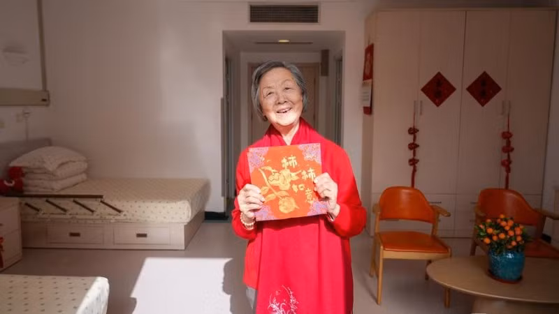 Một người phụ nữ lớn tuổi cầm trên tay tác phẩm thủ công của mình tại một trung tâm chăm sóc sức khỏe người cao tuổi. (Ảnh: Tân Hoa Xã)