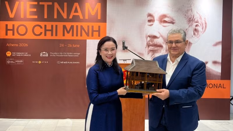 Giám đốc Khu Di tích Chủ tịch Hồ Chí Minh tại Phủ Chủ tịch Lê Thị Phượng trao tặng Tổng Bí thư Đảng Cộng sản Hy Lạp Dimitris Koutsoumpas mô hình Nhà sàn Bác Hồ. (Ảnh: Ban tổ chức)