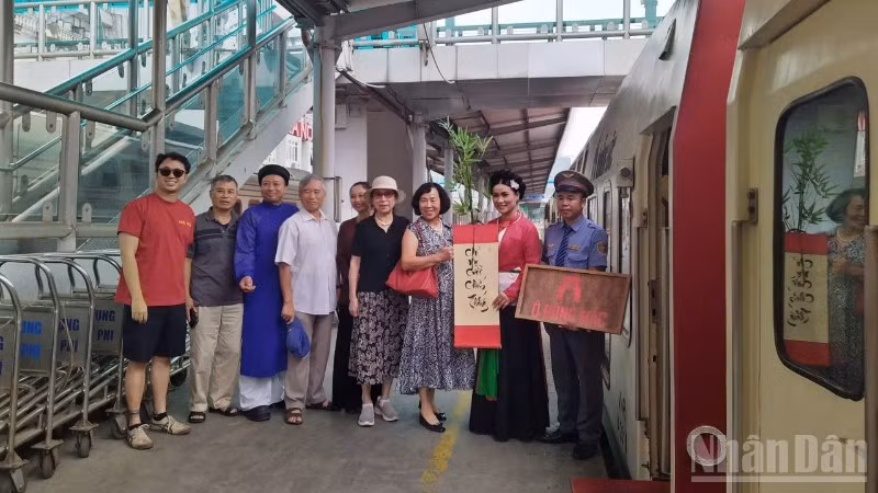 Du khách đi tàu di sản "tàu Hà Nội 5 cửa Ô" chụp ảnh lưu niệm cùng nhân viên phục vụ tàu.