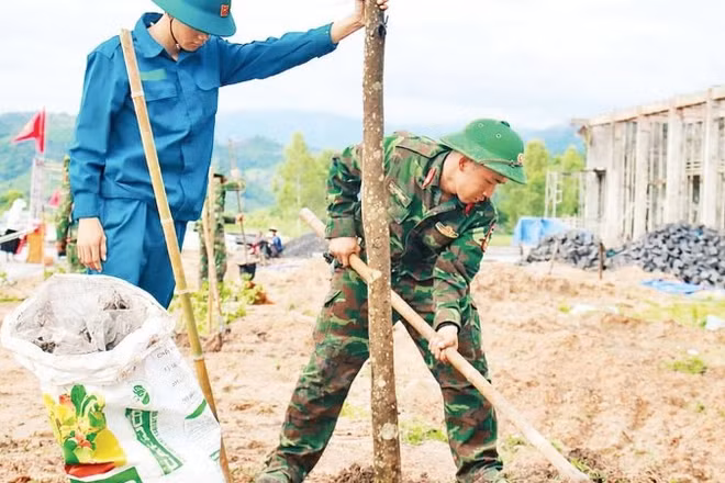 Cán bộ, chiến sĩ Đại đội Bộ binh 1 cùng lực lượng xung kích giúp người dân xây dựng khu tái định cư tại xã Ia Hiao.