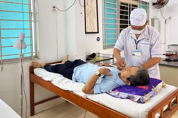 Y sĩ Nguyễn Hữu Đức điều trị cho bệnh nhân (Ảnh: NGUYỄN TRUNG)