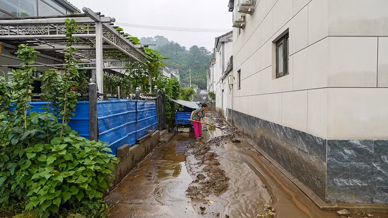 Người dân dọn bùn đất sau mưa lũ tại quận Mật Vân, Bắc Kinh, Trung Quốc. (Ảnh: THX/TTXVN)