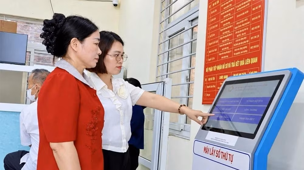 Cán bộ Trung tâm Phục vụ hành chính công xã Xuân Lãng hướng dẫn người dân sử dụng thiết bị lấy số thứ tự.
