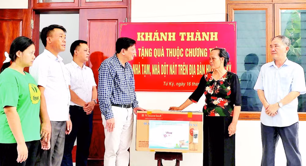 Đại diện chính quyền địa phương tặng quà gia đình bà Phạm Thị Thoa (ở xã Lạc Phượng) được hỗ trợ xây nhà mới.
