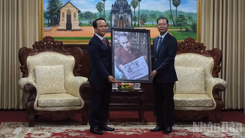 Phó Bí thư Thường trực Thành ủy Đà Nẵng Nguyễn Đình Vĩnh trao tặng bức ảnh Bác Hồ đọc Báo Nhân Dân cho lãnh đạo tỉnh Savannakhet. (Ảnh: ANH ĐÀO)