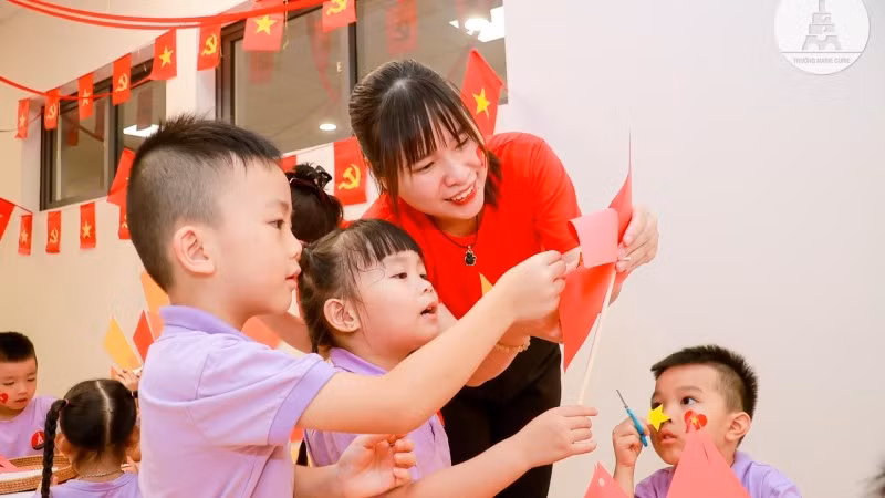 Cô và trò cùng nhau làm lá cờ đỏ sao vàng.