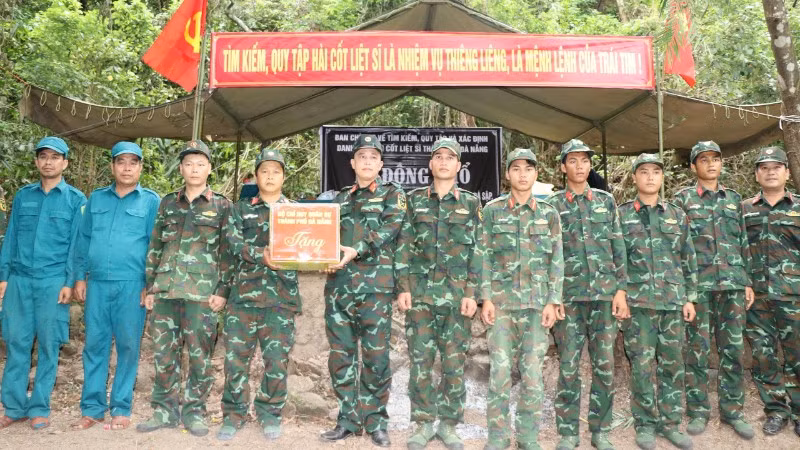 Đại tá Trần Hữu Ích trao quà, động viên cán bộ, chiến sĩ Đội tìm kiếm, quy tập hài cốt liệt sĩ của Bộ Chỉ huy Quân sự thành phố đang thực hiện nhiệm vụ tại hiện trường.