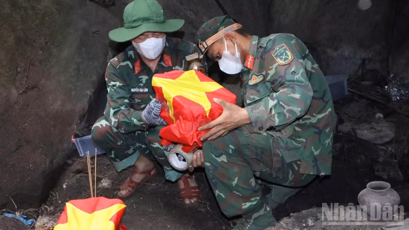 Những hài cốt liệt sĩ được bộ đội cẩn trọng phủ cờ Tổ quốc, đưa ra khỏi hang sâu.