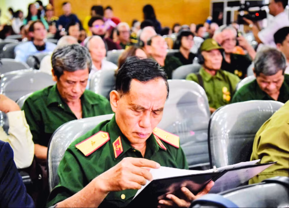Thiếu tướng Trịnh Xuân Chuyền đọc những dòng chữ trong hồ sơ của đồng đội được trao trả. (Ảnh GIA KHÁNH)