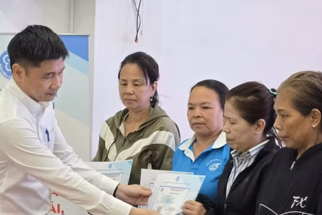 Ông Trần Dũng Hà, Phó Giám đốc Bảo hiểm xã hội Thành phố Hồ Chí Minh trao thẻ Bảo hiểm y tế cho phụ nữ có hoàn cảnh khó khăn. (Ảnh: QUÝ HIỀN)