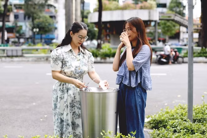 Các bạn trẻ sử dụng trụ nước uống tại vòi đặt ở Khu vực Hồ Con Rùa. (Ảnh: QUÝ HIỀN)