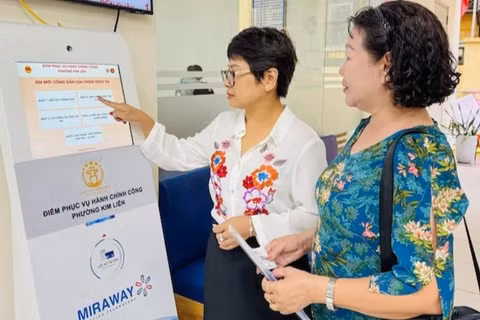 Công chức tại Điểm tiếp nhận, phục vụ hành chính công phường Kim Liên hướng dẫn người dân lấy số để thực hiện các thủ tục hành chính. (Ảnh: KHÁNH HUY)
