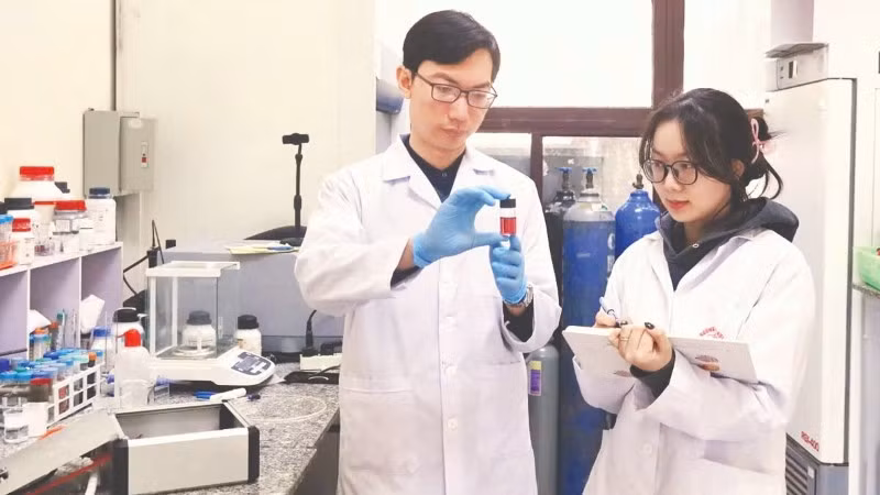 Tiến sĩ Nguyễn Nhật Linh hướng dẫn sinh viên kiểm tra mẫu sản phẩm hạt nano vàng thu được từ quá trình tổng hợp plasma. (Ảnh: MINH ĐỨC)