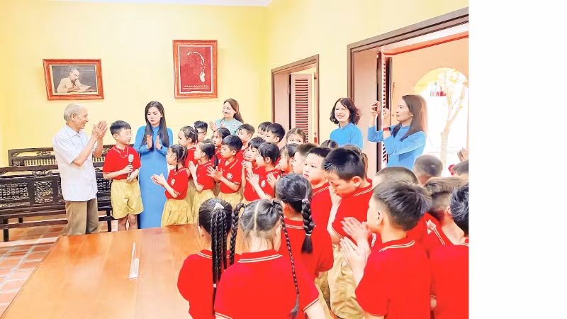 Ông Công Ngọc Dũng kể những câu chuyện về Bác Hồ với cô trò Trường tiểu học Phú Thượng khi các em học sinh học tiết học Lịch sử địa phương tại di tích Nhà cụ Nguyễn Thị An.