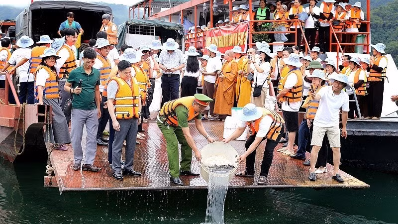 Cán bộ, nhân dân phường Thống Nhất cùng tăng ni, phật tử thả cá giống xuống tại lòng hồ Hòa Bình.