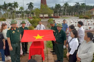 Nghi thức phủ Quốc kỳ, trước khi đưa liệt sĩ Lê Duy Nhẫn về quê hương. (Ảnh: THÀNH TRUNG)